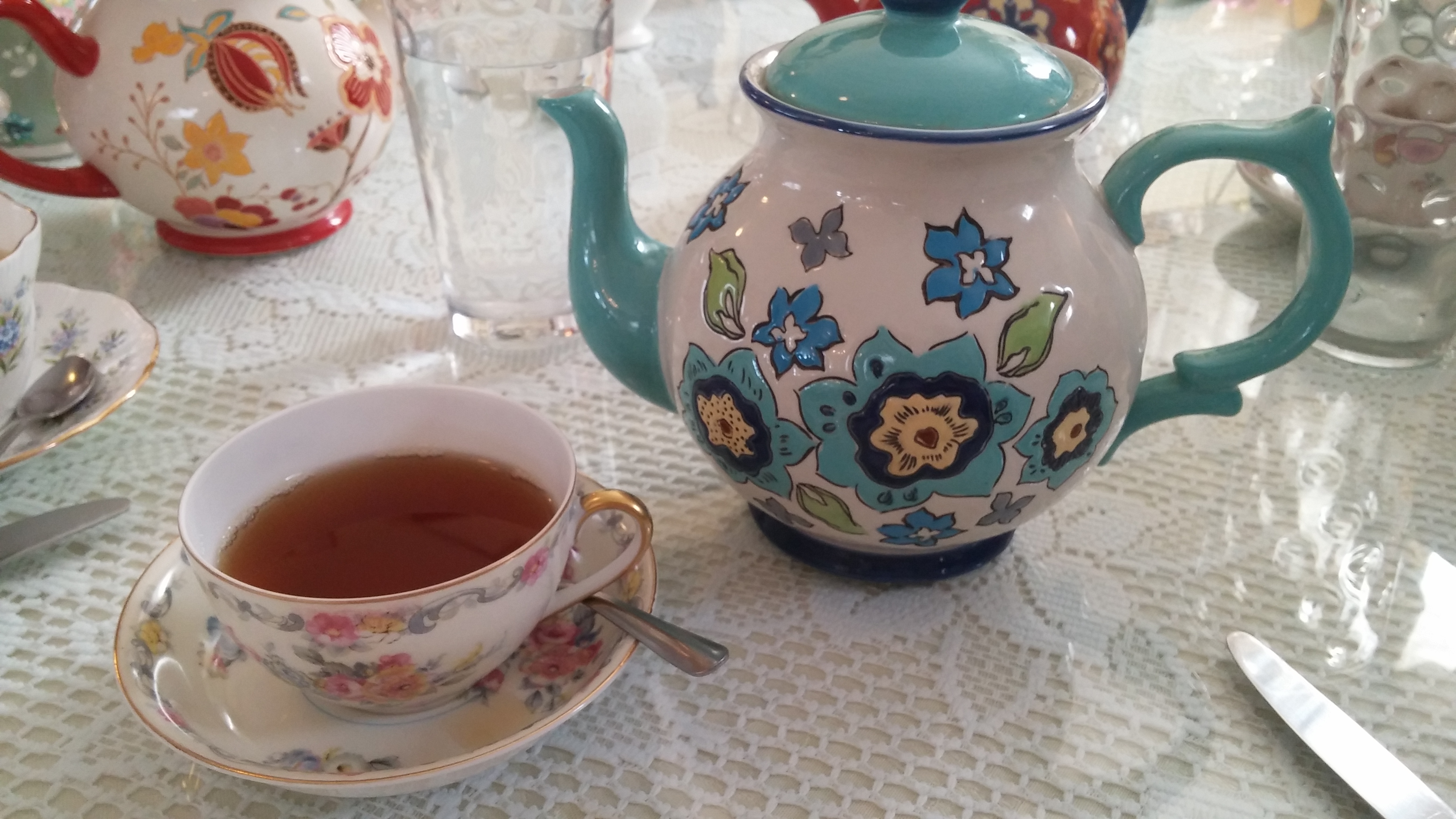 Tea cup filled with tea and a tea pot